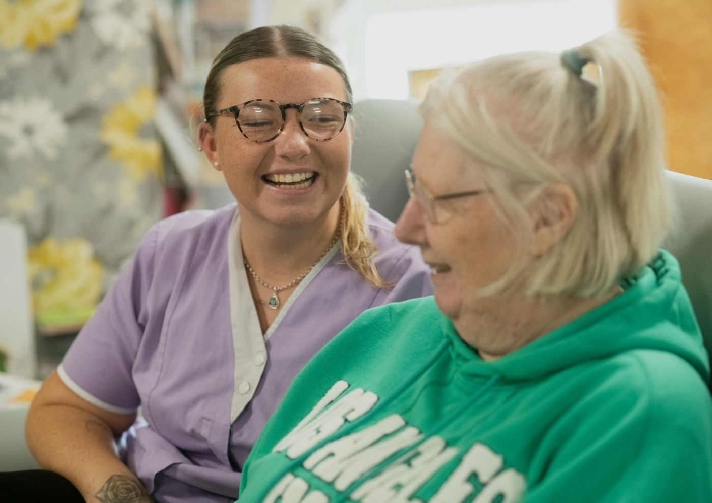 A carer supporting an elderly resident with a tablet